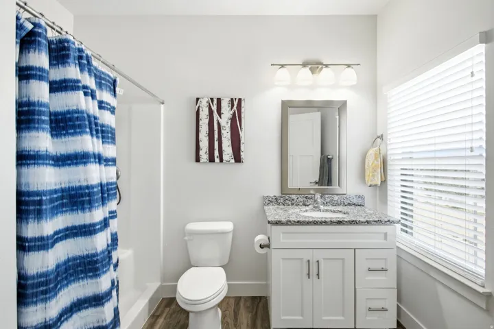 White vanity with granite-style countertop, undermount sink, and brushed nickel hardware