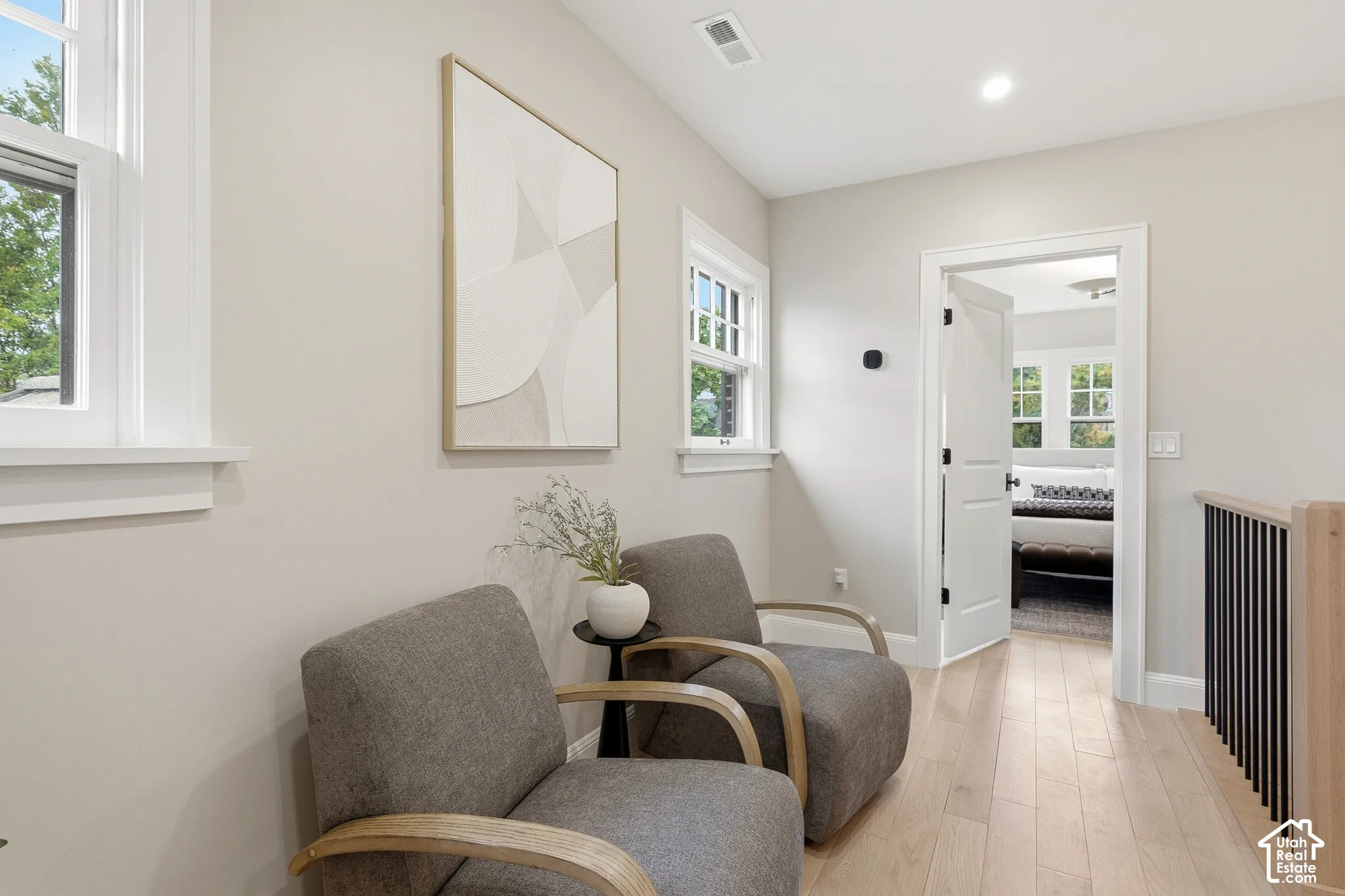Light wood-finish flooring with white trim, recessed lighting, and a contemporary railing