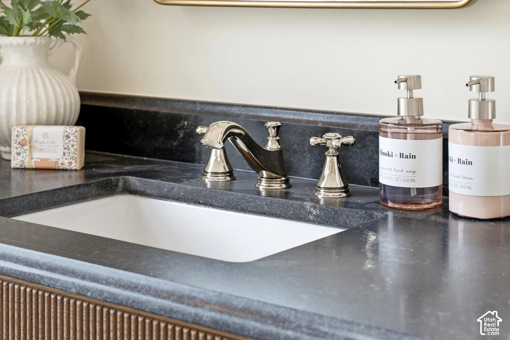 Integrated white rectangular sink with a three-piece polished nickel faucet set, set within a dark stone countertop