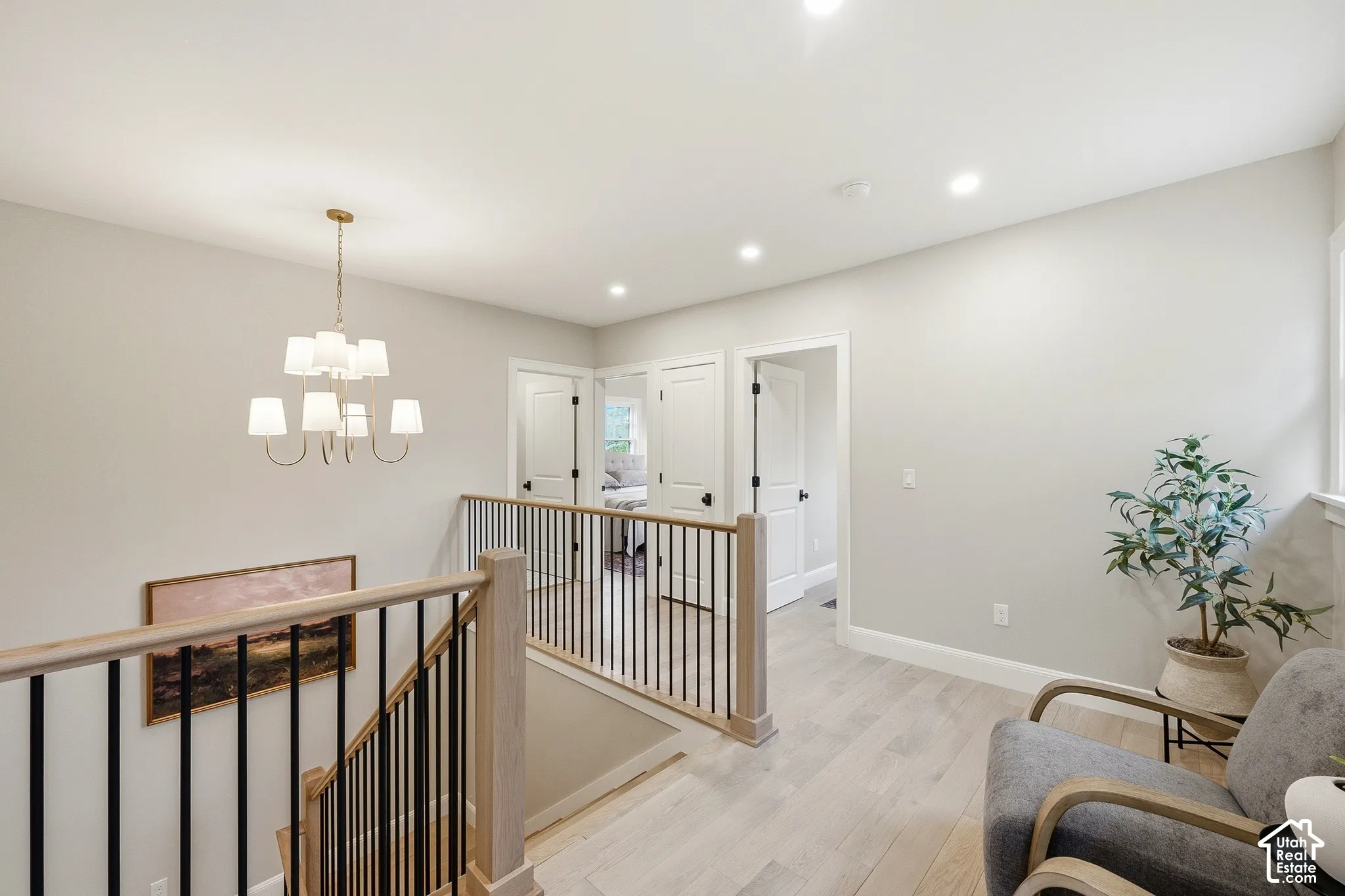 Upper landing with wood-finish flooring, recessed lighting, and a modern chandelier