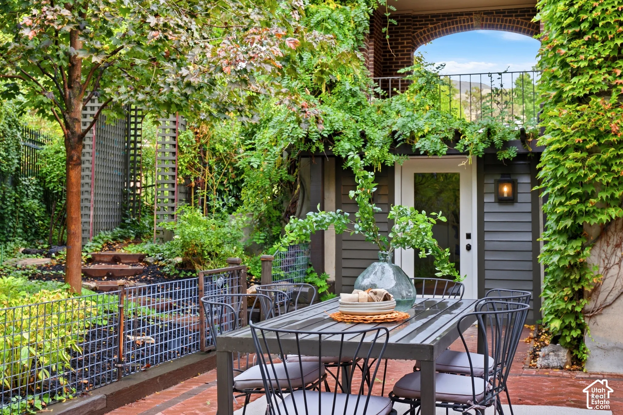 Brick paver patio featuring a wrought iron outdoor dining set and view of door to the gym.