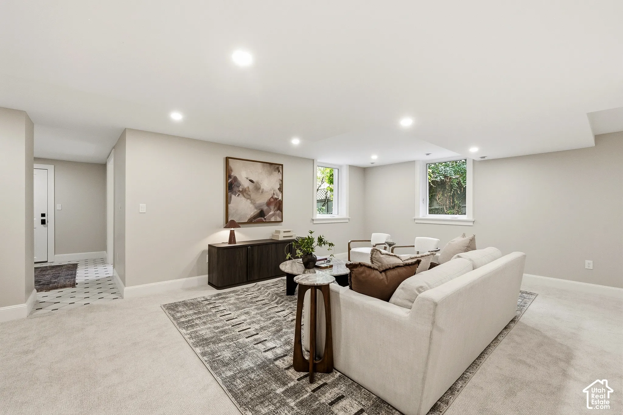 Recessed lighting illuminates the open living area with light gray carpeting