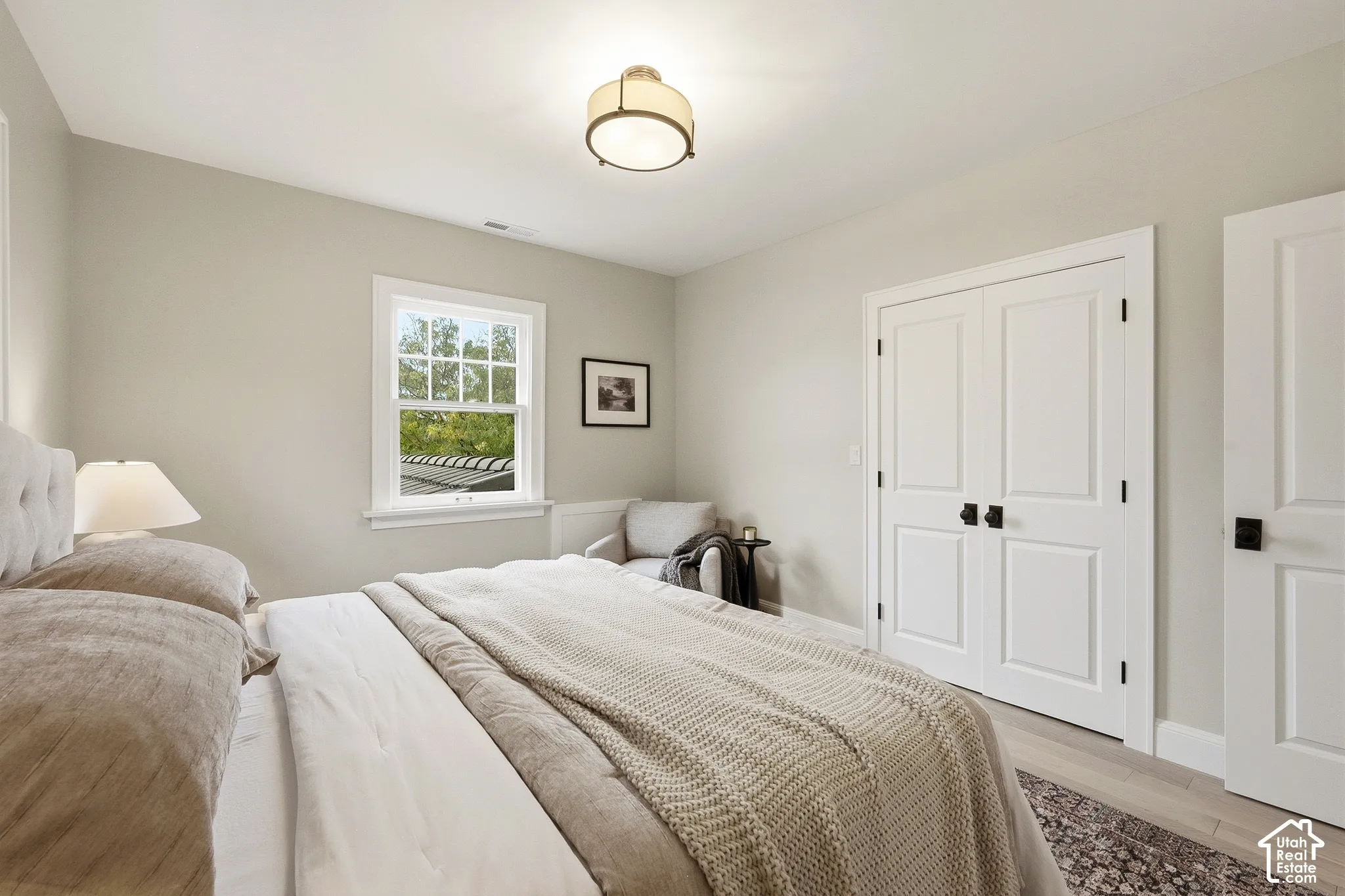 Third Bedroom. Recessed window with white trim, double panel doors with black hardware, wood-finish flooring, and a flush mount ceiling fixture