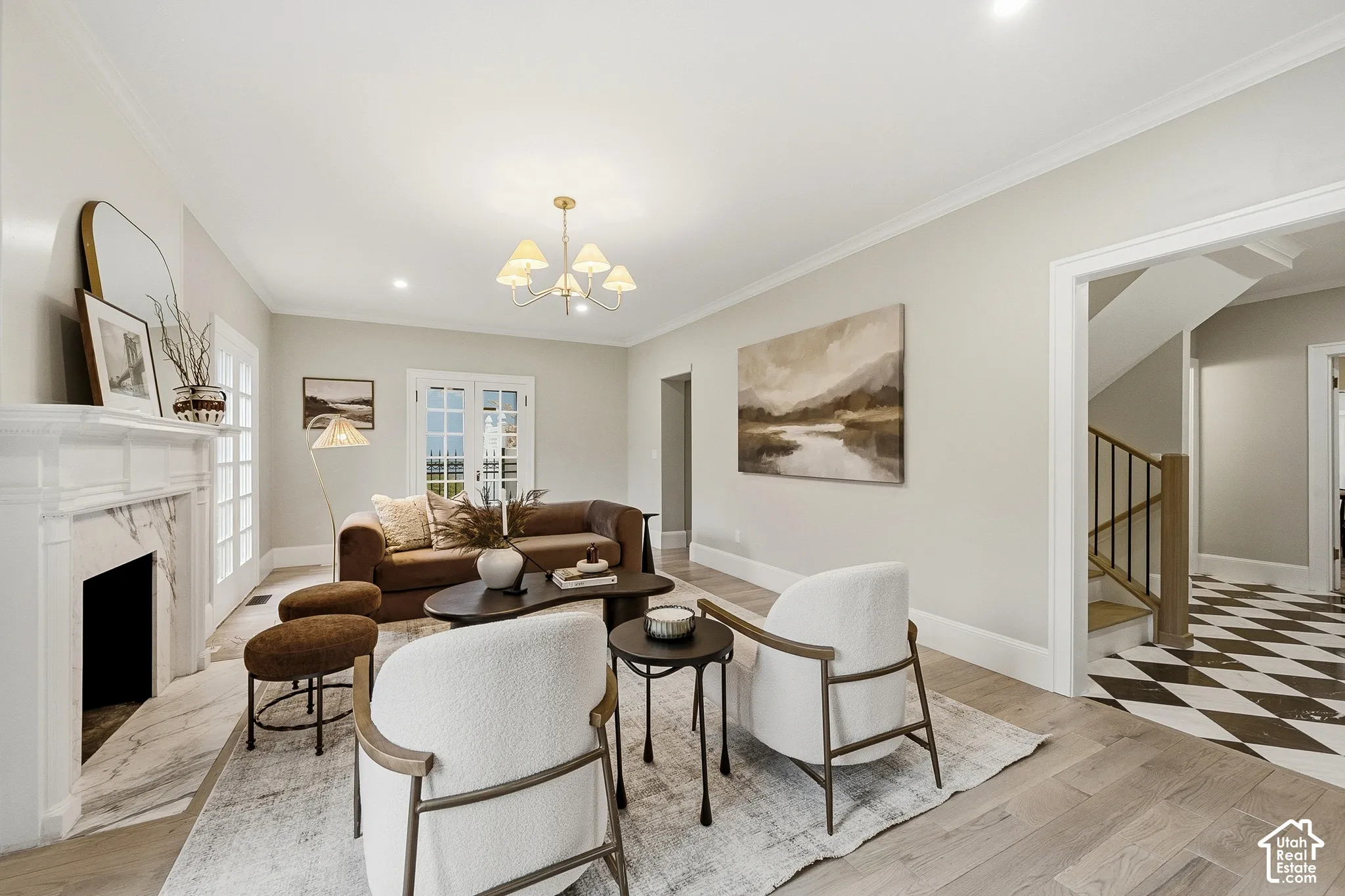 Living area featuring light wood-finish flooring, a decorative fireplace with a marble surround and white mantel, and double French doors