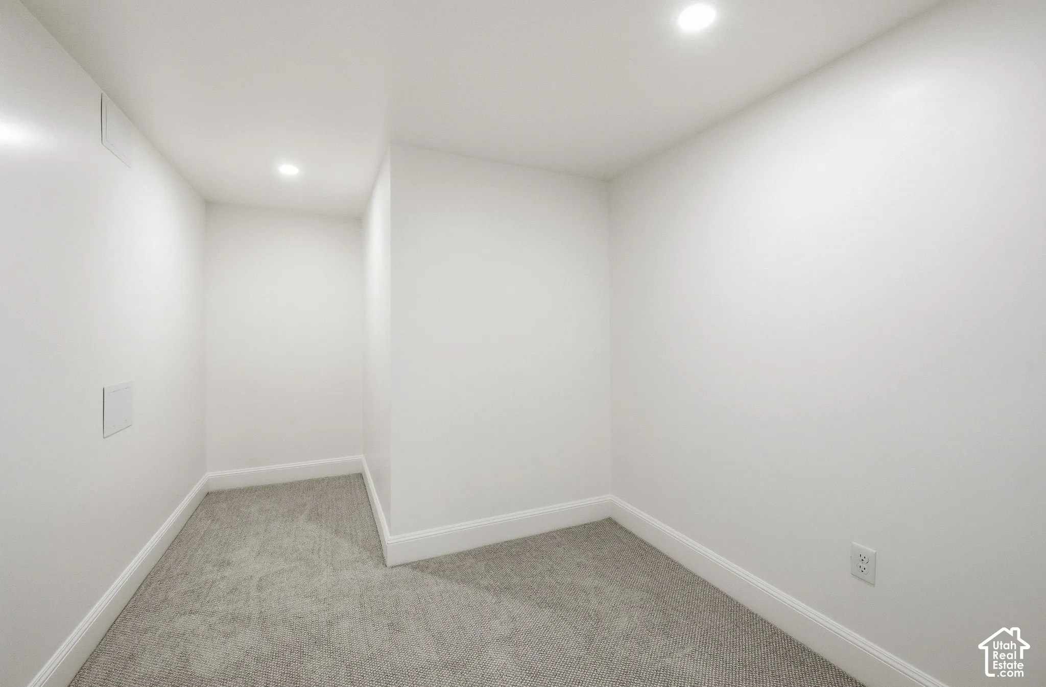 Recessed ceiling lighting illuminates a carpeted interior with white walls