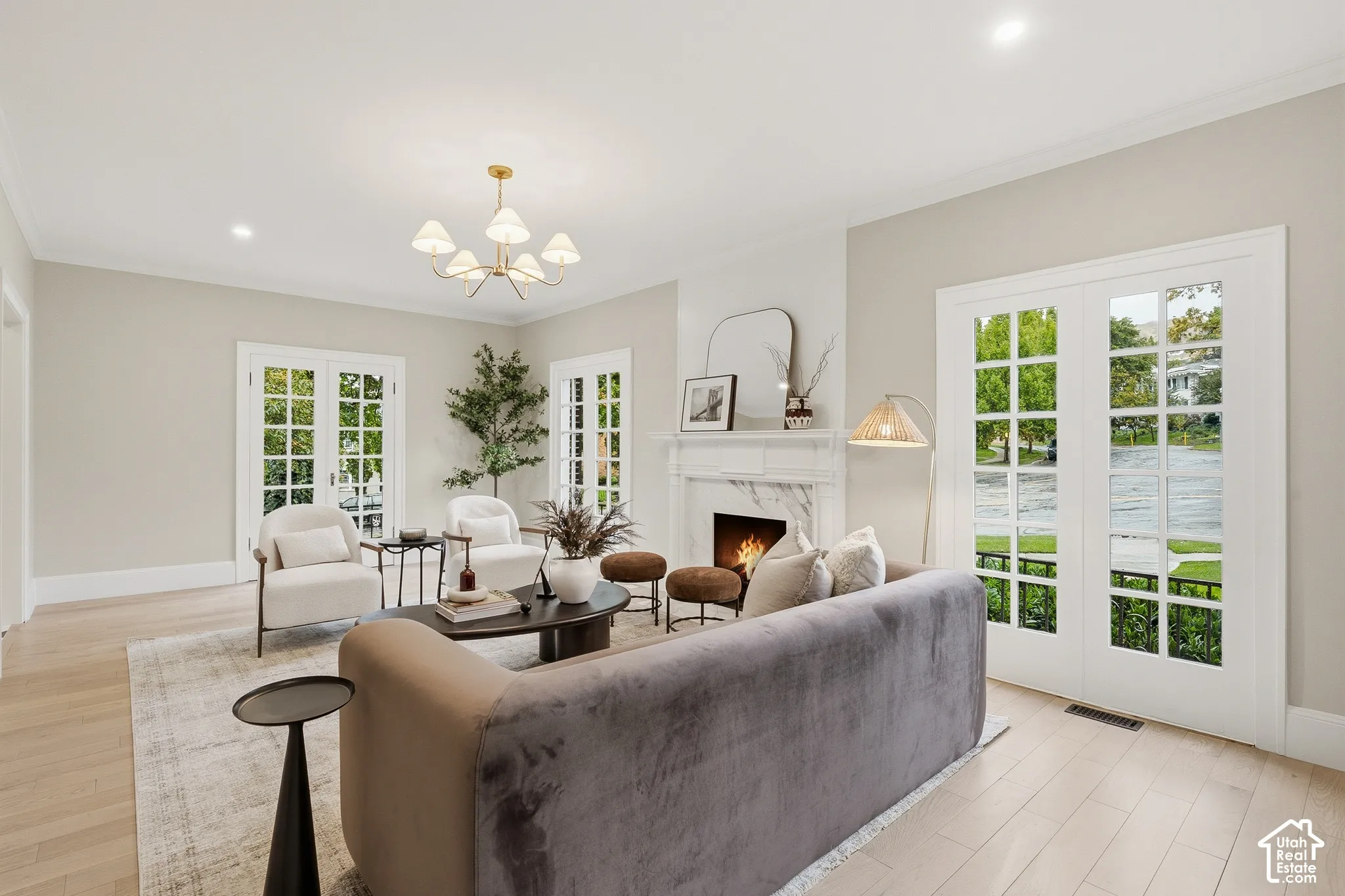 Light wood-finish flooring, recessed lighting, and a chandelier illuminate this living space
