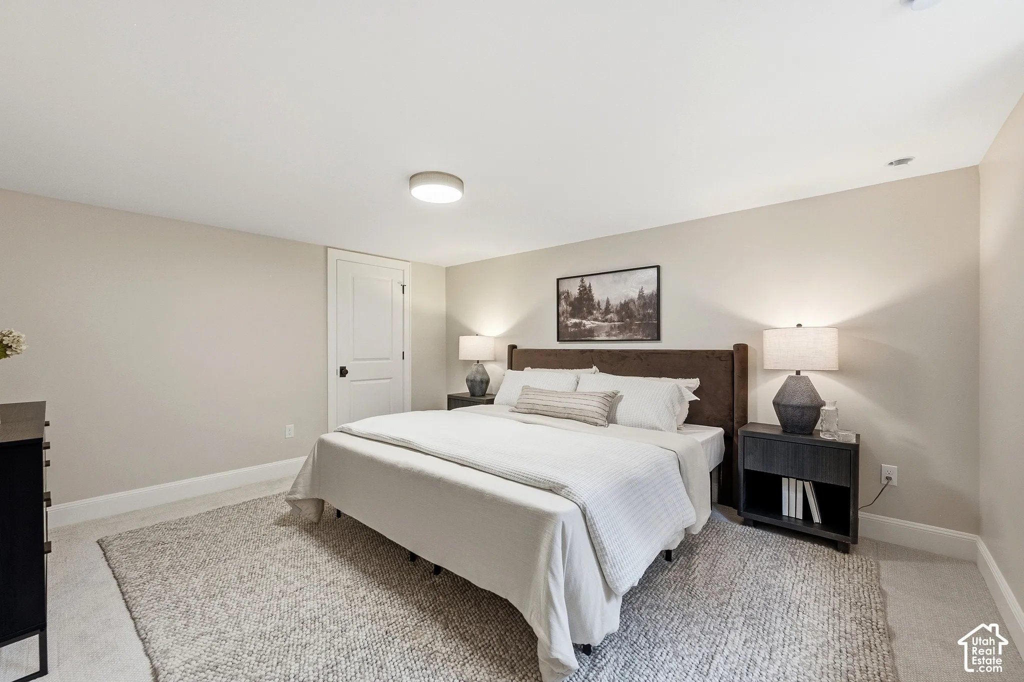 Carpeted flooring, recessed ceiling lighting, light-toned wall paint, white trim, and a paneled door with dark hardware