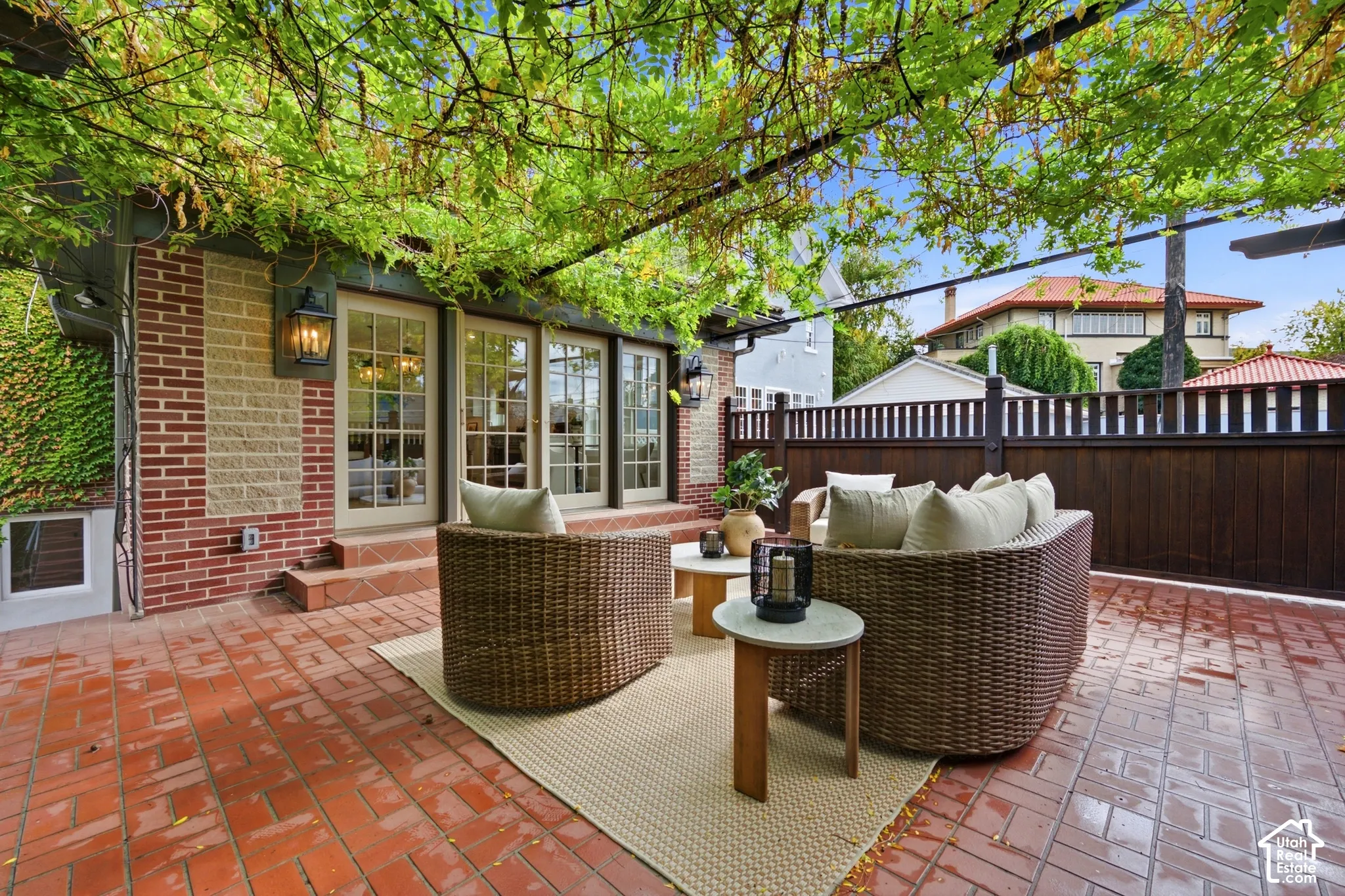 Brick patio featuring a wisteria vine-covered pergola, French doors, and exterior wall lanterns