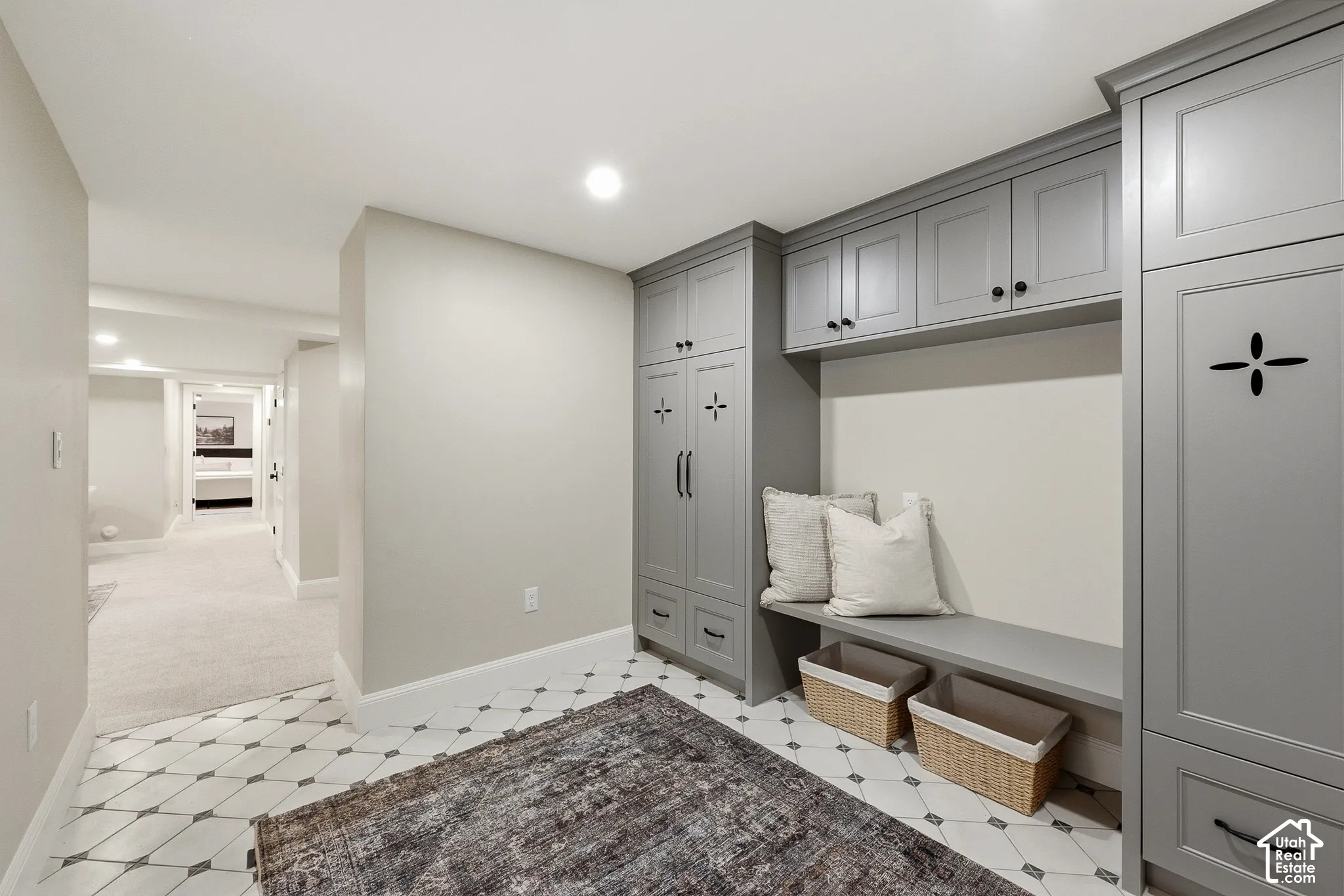 Built-in cabinetry with ample storage, integrated bench seating, recessed lighting, patterned tile flooring, and carpeted hallway