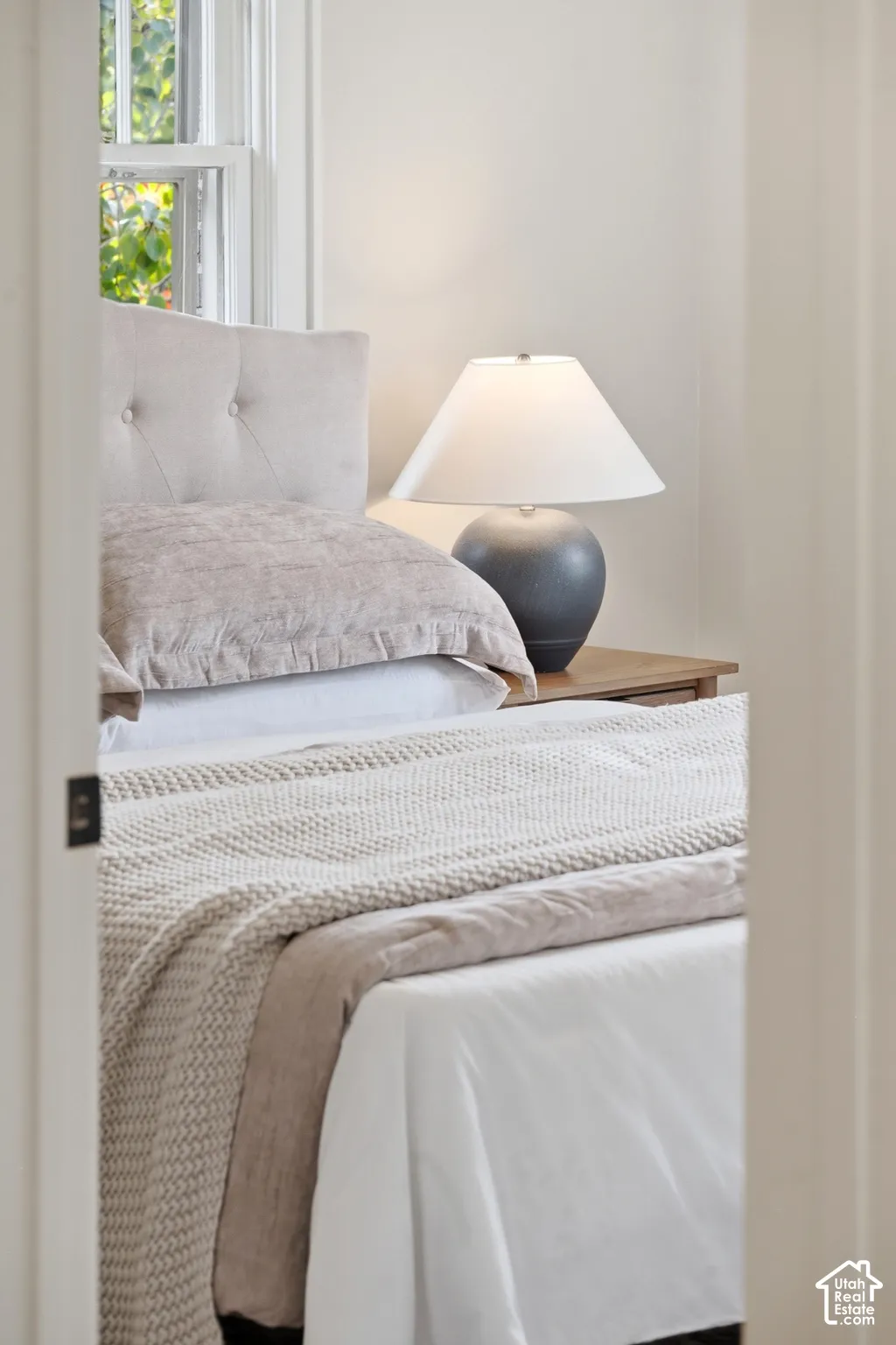 Window with natural light, tufted headboard, and light-toned walls