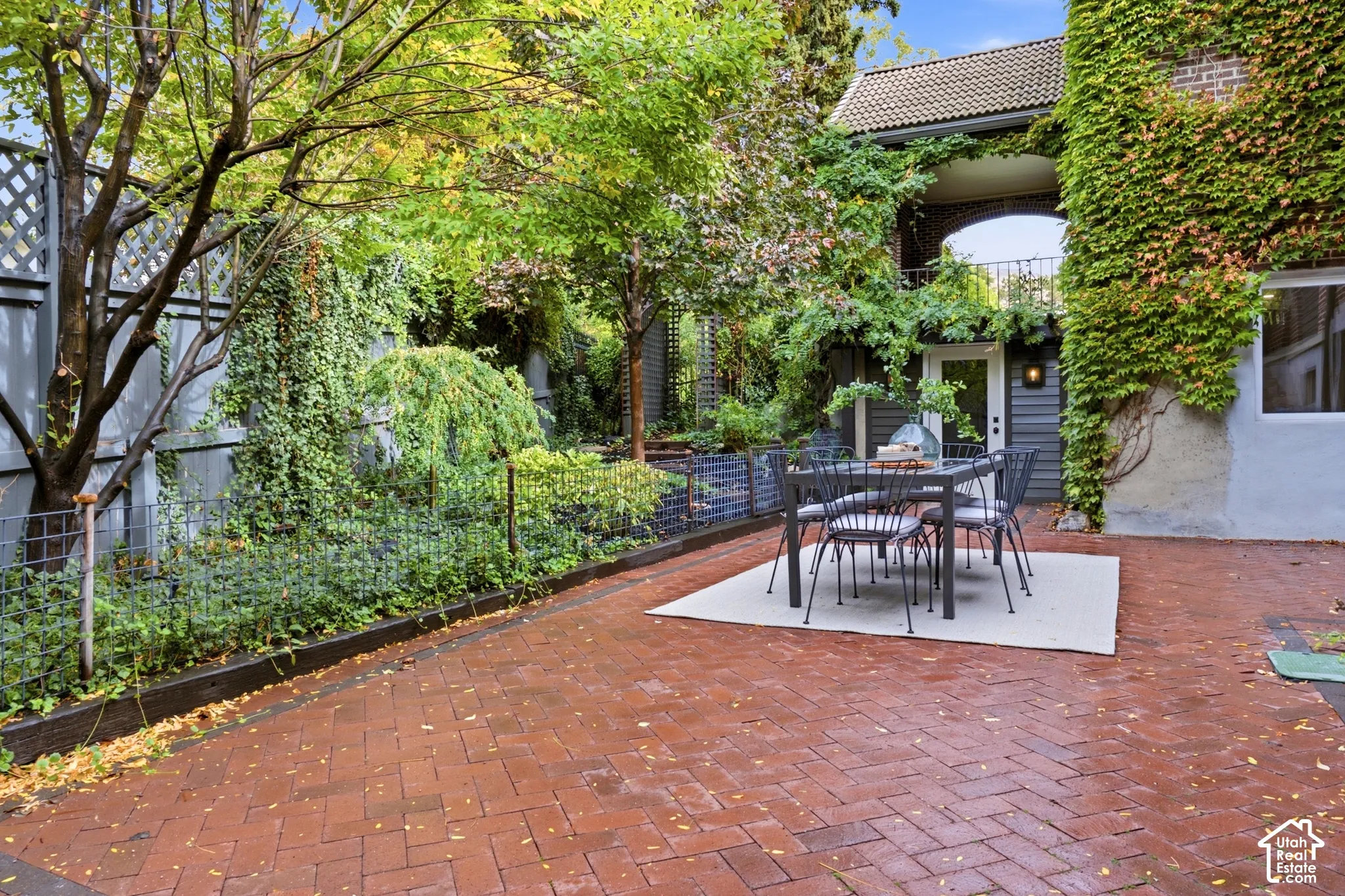 Brick paver patio with a lattice fence and mature landscaping
