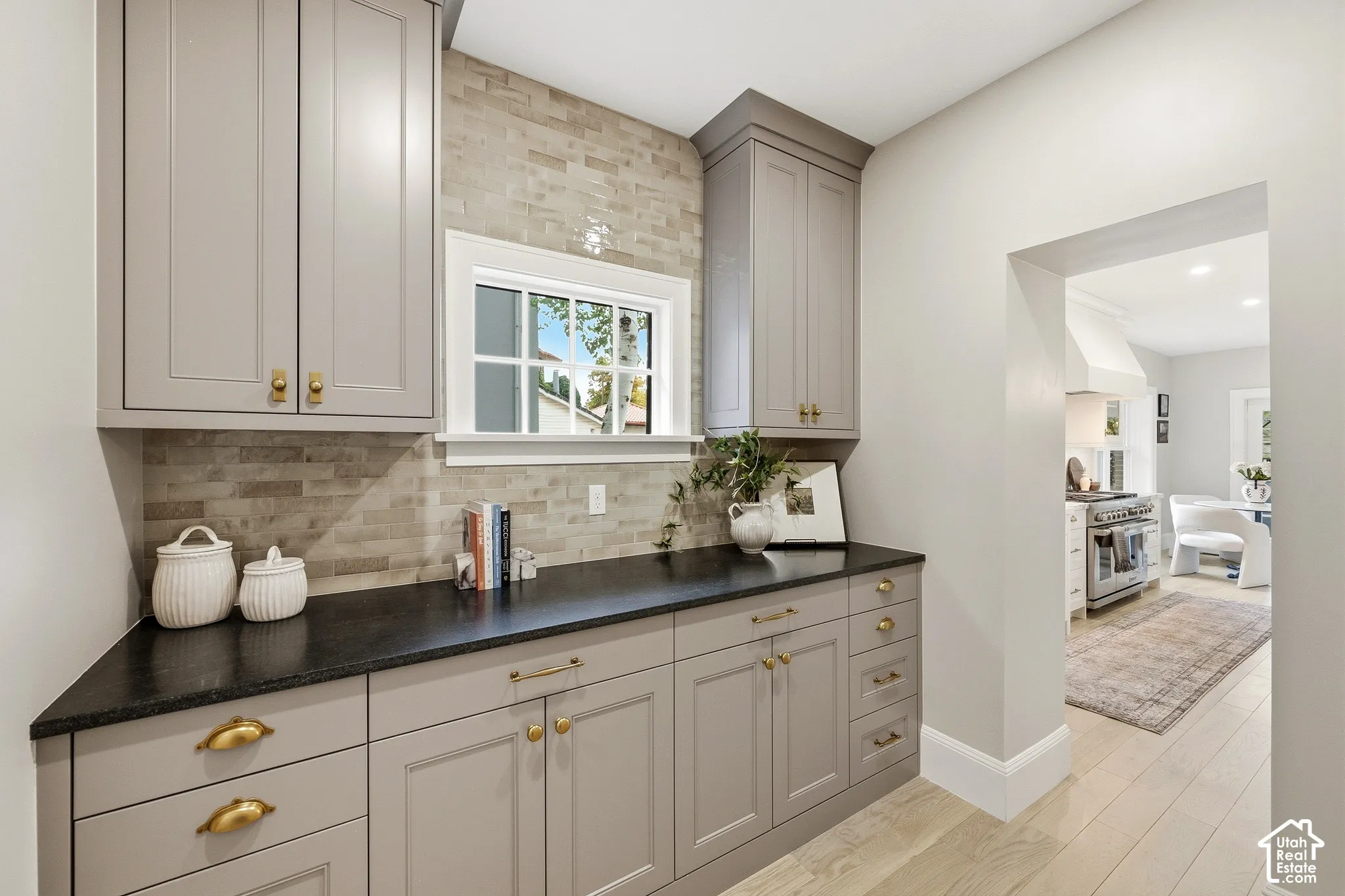 Butler's Pantry with built-in cabinetry, brass hardware, black mist countertops, and a subway tile backsplash
