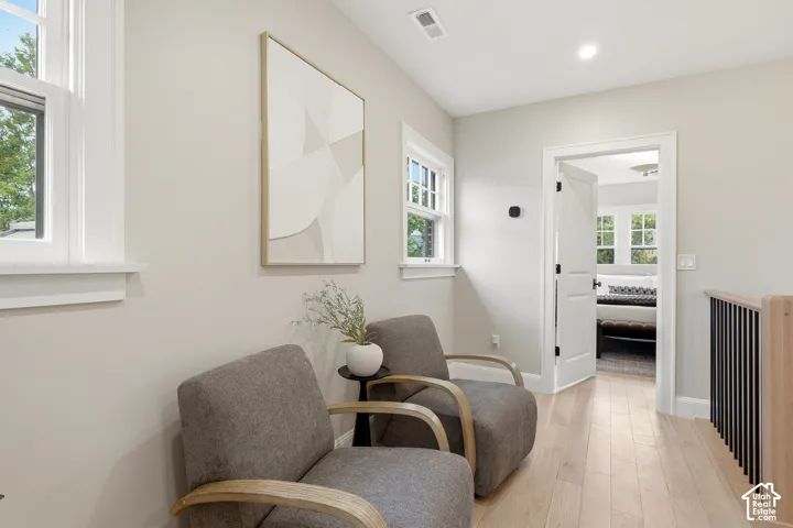 Light wood-finish flooring with white trim, recessed lighting, and a contemporary railing