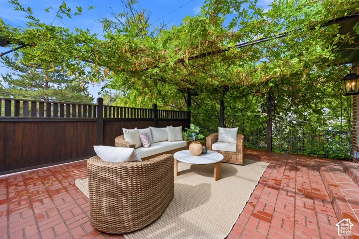 Brick paver patio with a vine-covered pergola, adjacent to a dark wood privacy fence, and antique style lanterns