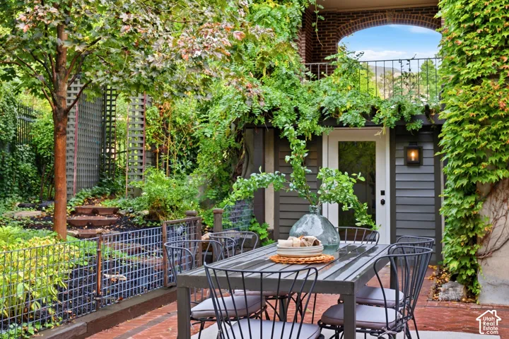 Brick paver patio featuring a wrought iron outdoor dining set and view of door to the gym.