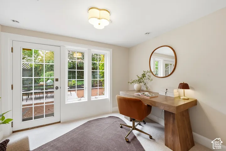 Light-filled interior featuring a glass-paneled door, two fixed windows, and a flush-mount ceiling light with charming door opening out onto lower patio and garden