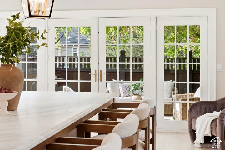 White grid-pattern French doors, light wood-finish flooring, and a white countertop