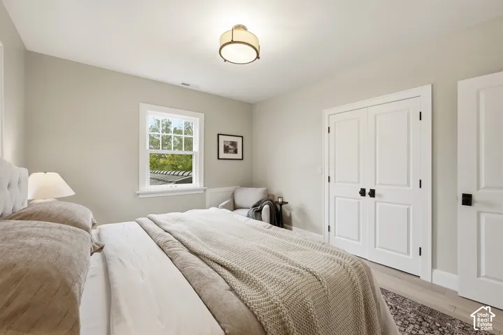 Third Bedroom. Recessed window with white trim, double panel doors with black hardware, wood-finish flooring, and a flush mount ceiling fixture