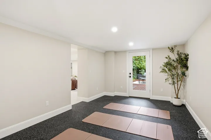 Recessed lighting illuminates the neutral-toned walls and dark, textured flooring