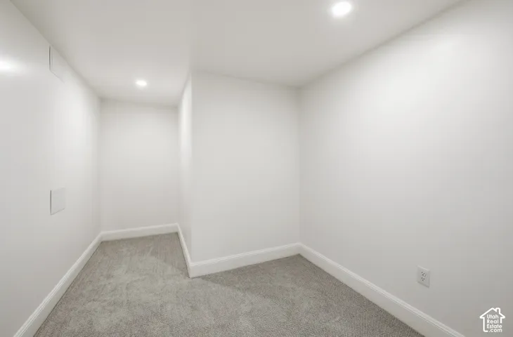 Recessed ceiling lighting illuminates a carpeted interior with white walls