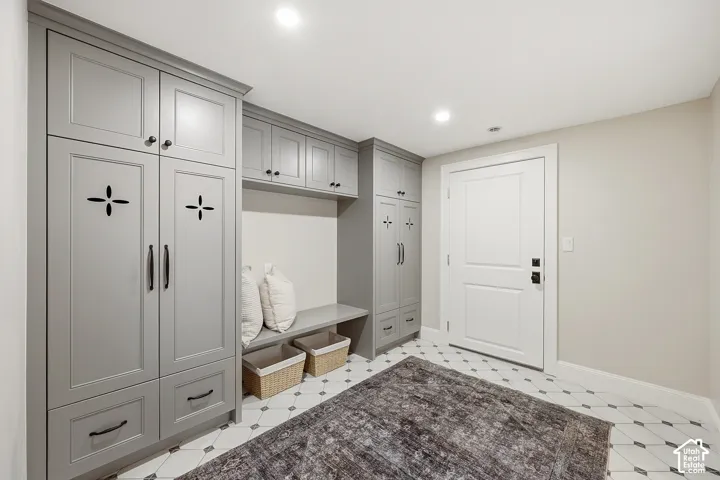 Built-in gray cabinetry with bronze hardware, integrated bench seating, recessed lighting, and patterned floor tiles