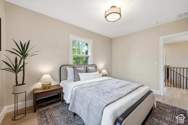 Second Bedroom. Light-toned walls with contrasting white trim, wood-finish flooring, and a flush-mount ceiling light fixture