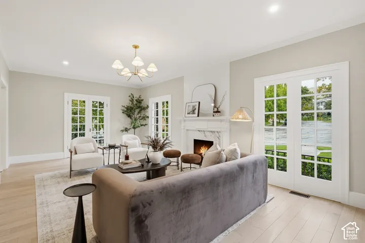 Light wood-finish flooring, recessed lighting, and a chandelier illuminate this living space