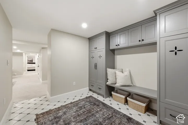 Built-in cabinetry with ample storage, integrated bench seating, recessed lighting, patterned tile flooring, and carpeted hallway