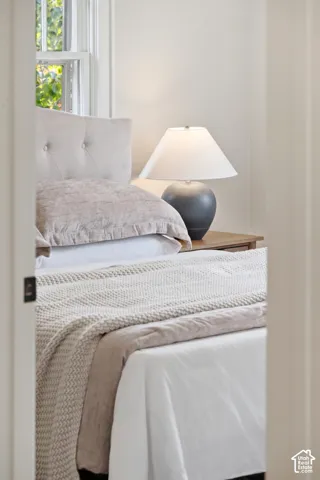 Window with natural light, tufted headboard, and light-toned walls