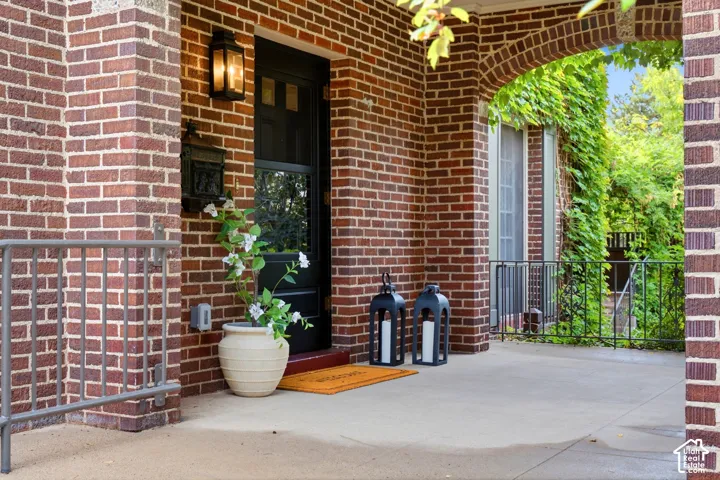 Brick exterior with a dark-paneled door, exterior wall lantern, and concrete porch