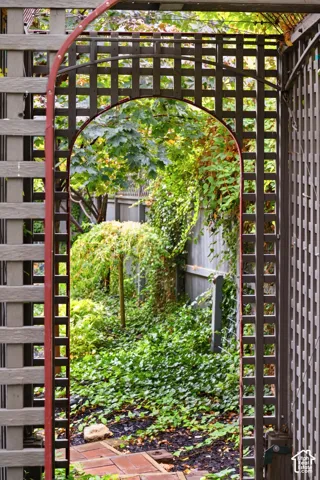 Lattice archway with an arched opening, brick paver pathway, and established ground cover