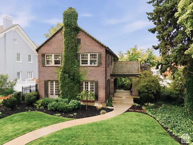 Traditional brick exterior featuring a multi-gabled roofline, decorative shutters, a covered porte-coch