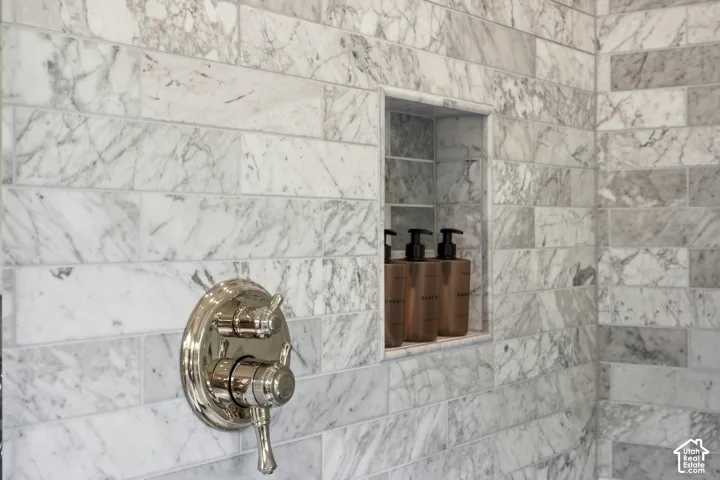 Marble-tiled shower surround with a polished nickel shower control and built-in recessed shelving