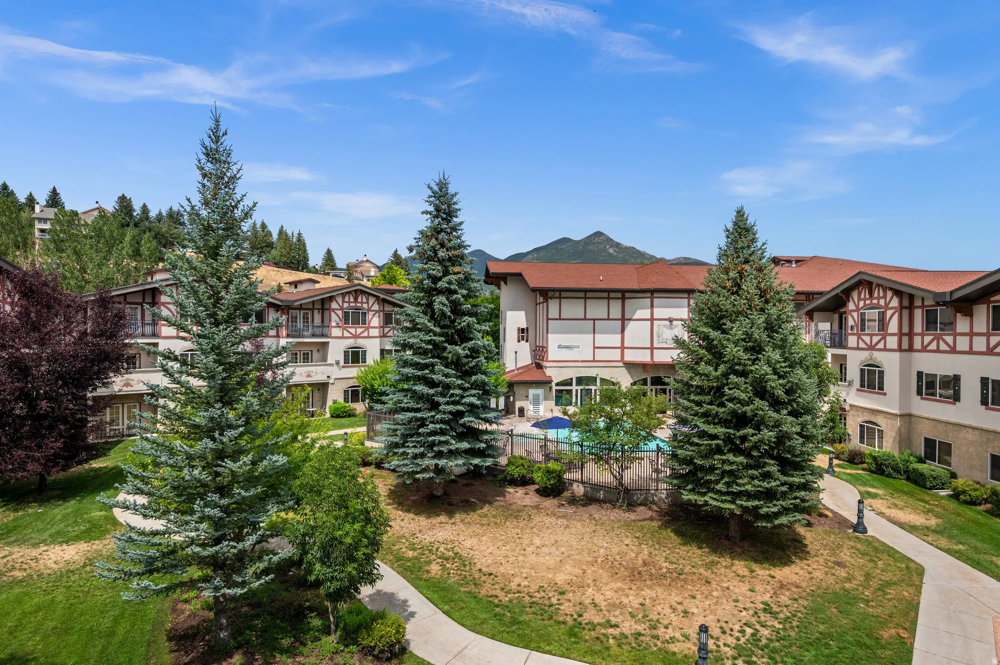 Multi-story building featuring stucco and timber framing, gabled roofs, and an outdoor swimming pool