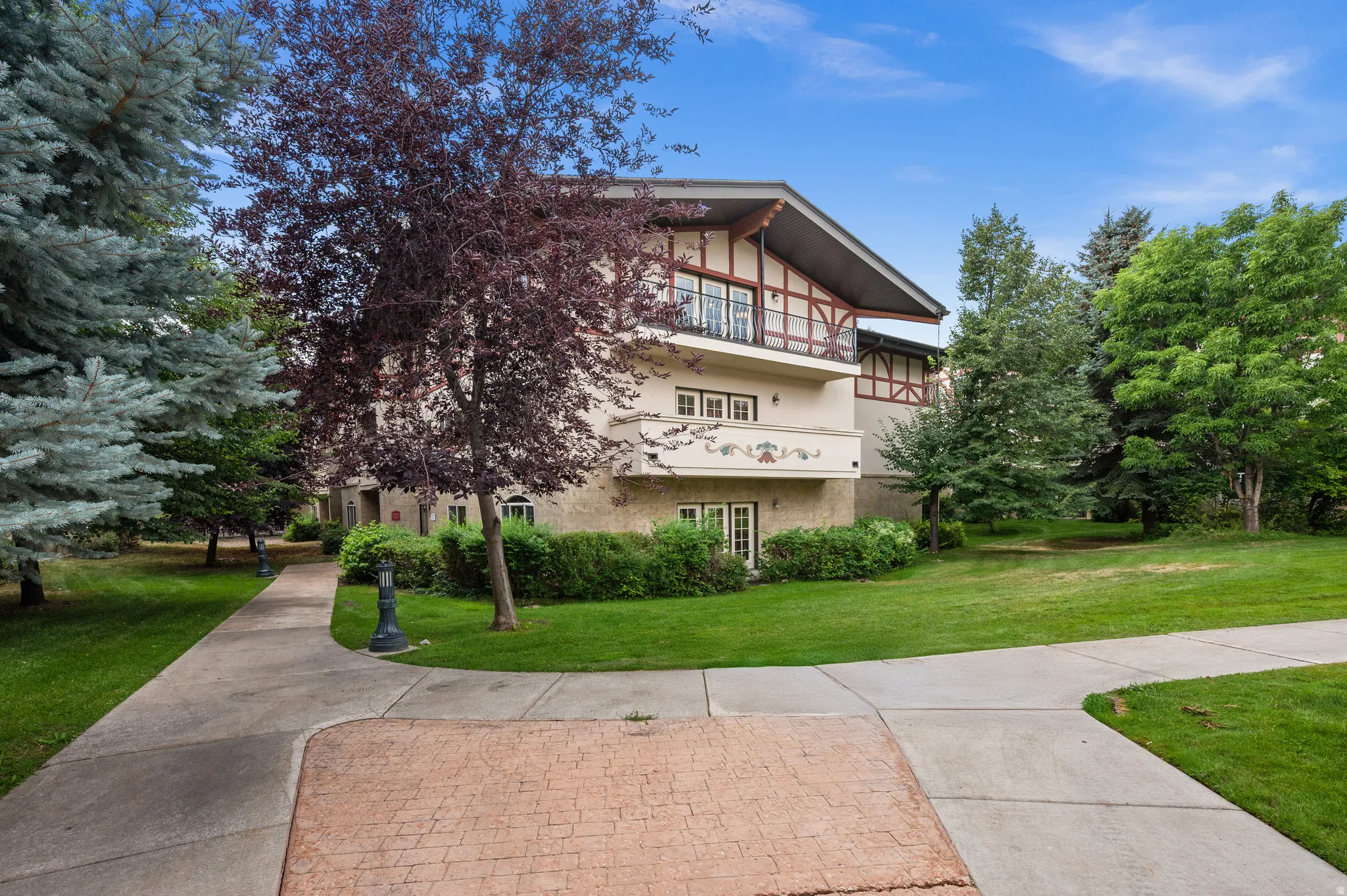 Stucco exterior with decorative timber accents, multiple balconies, and double glass doors