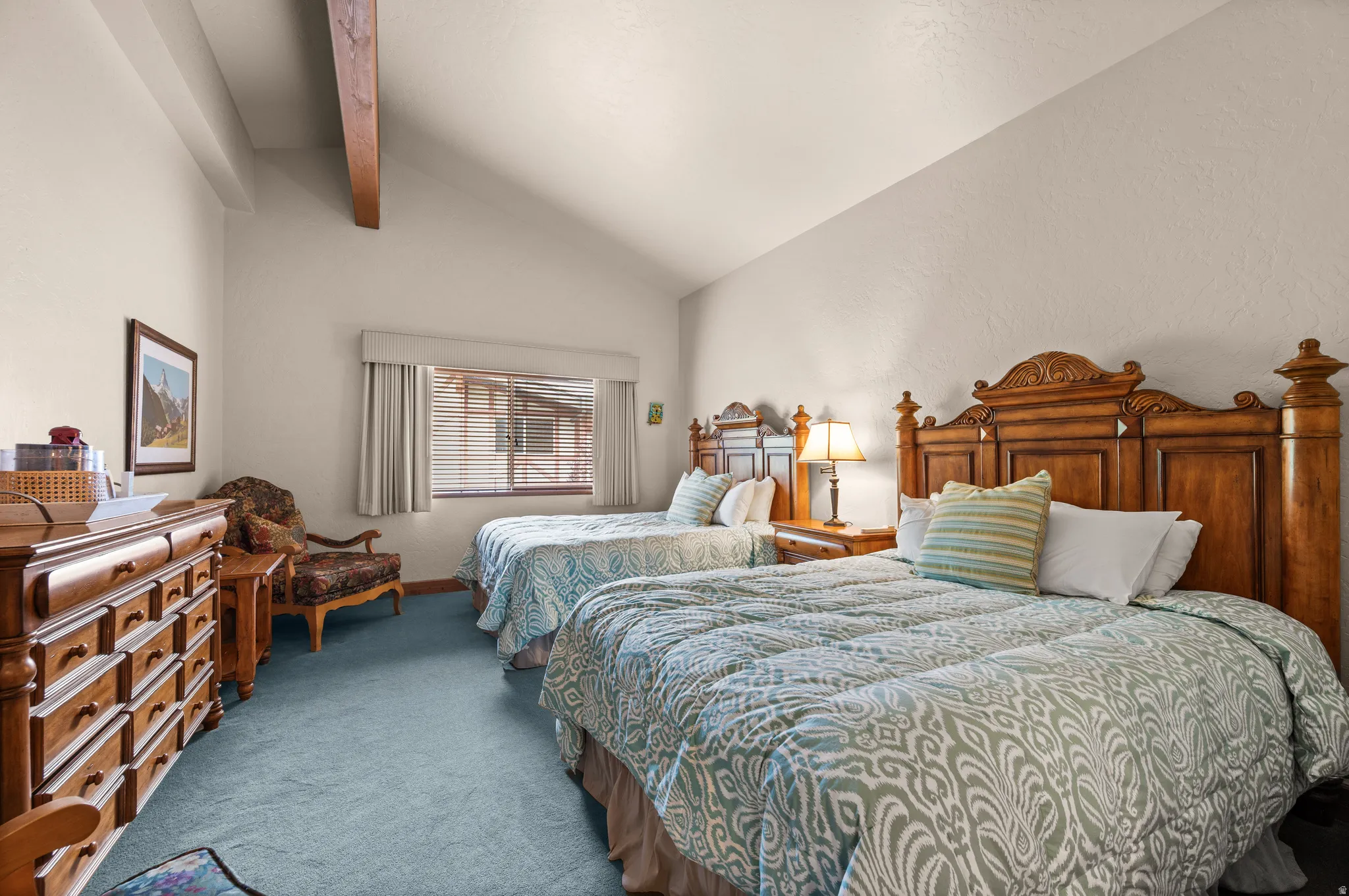Vaulted ceilings with exposed wood beams, a window with horizontal blinds, and wall-to-wall carpeting