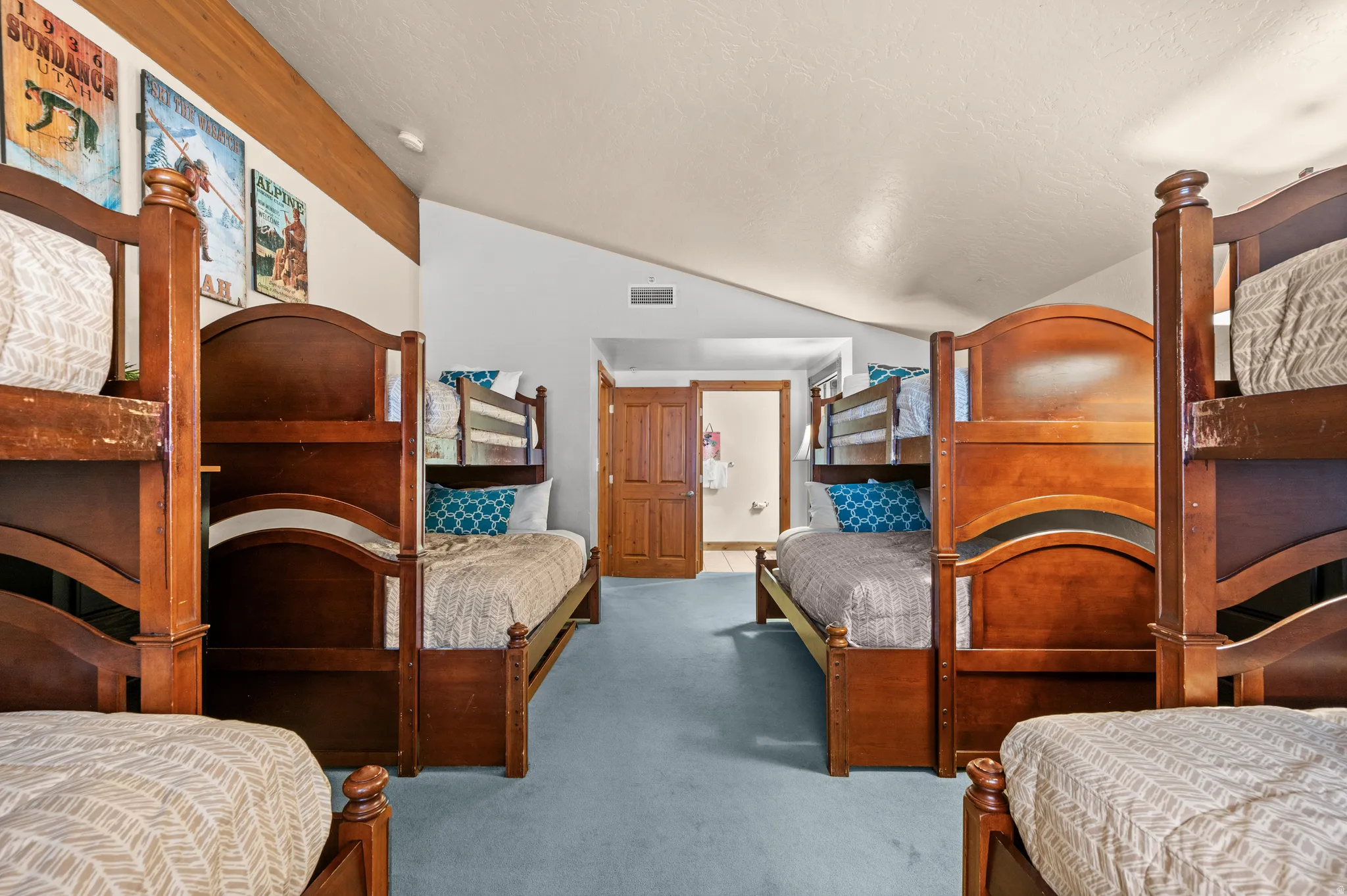 Vaulted ceilings, wood-finish accent wall, and light blue carpet flooring