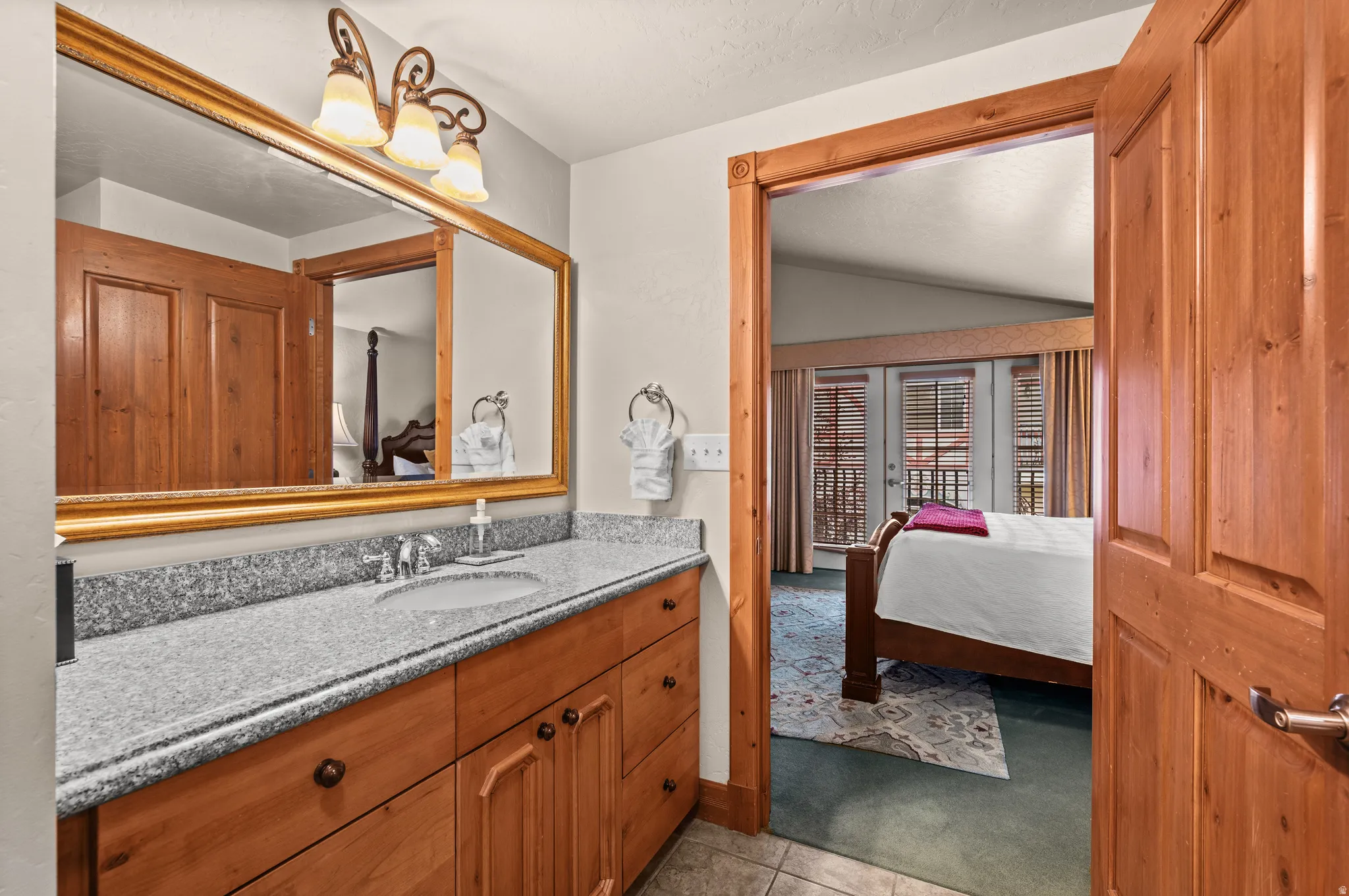 Vanity with a polished stone countertop, wood-finish cabinetry, and a framed mirror