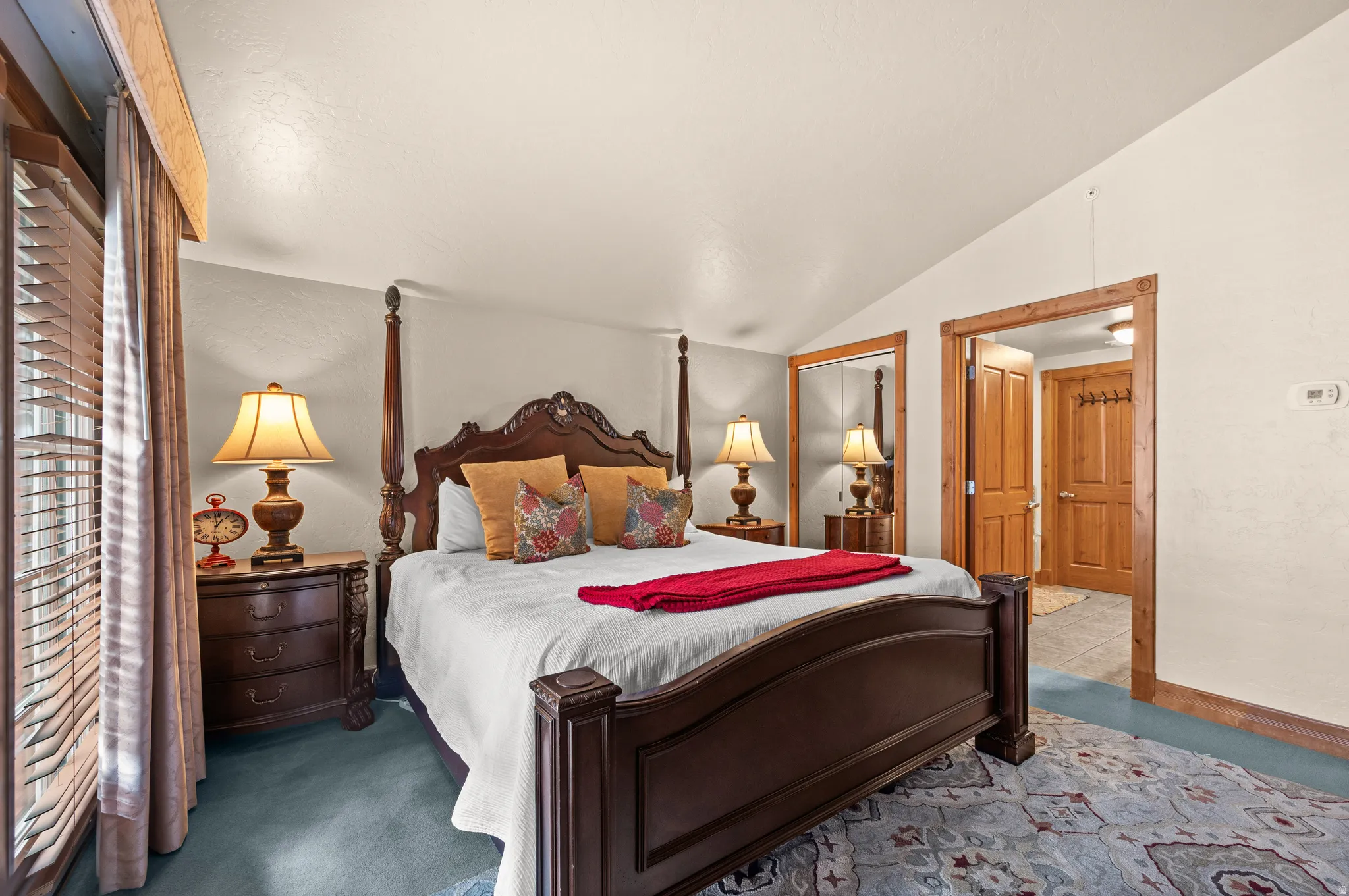 Vaulted ceiling with an exposed wood beam, wood-trimmed doorway, and a mirrored closet