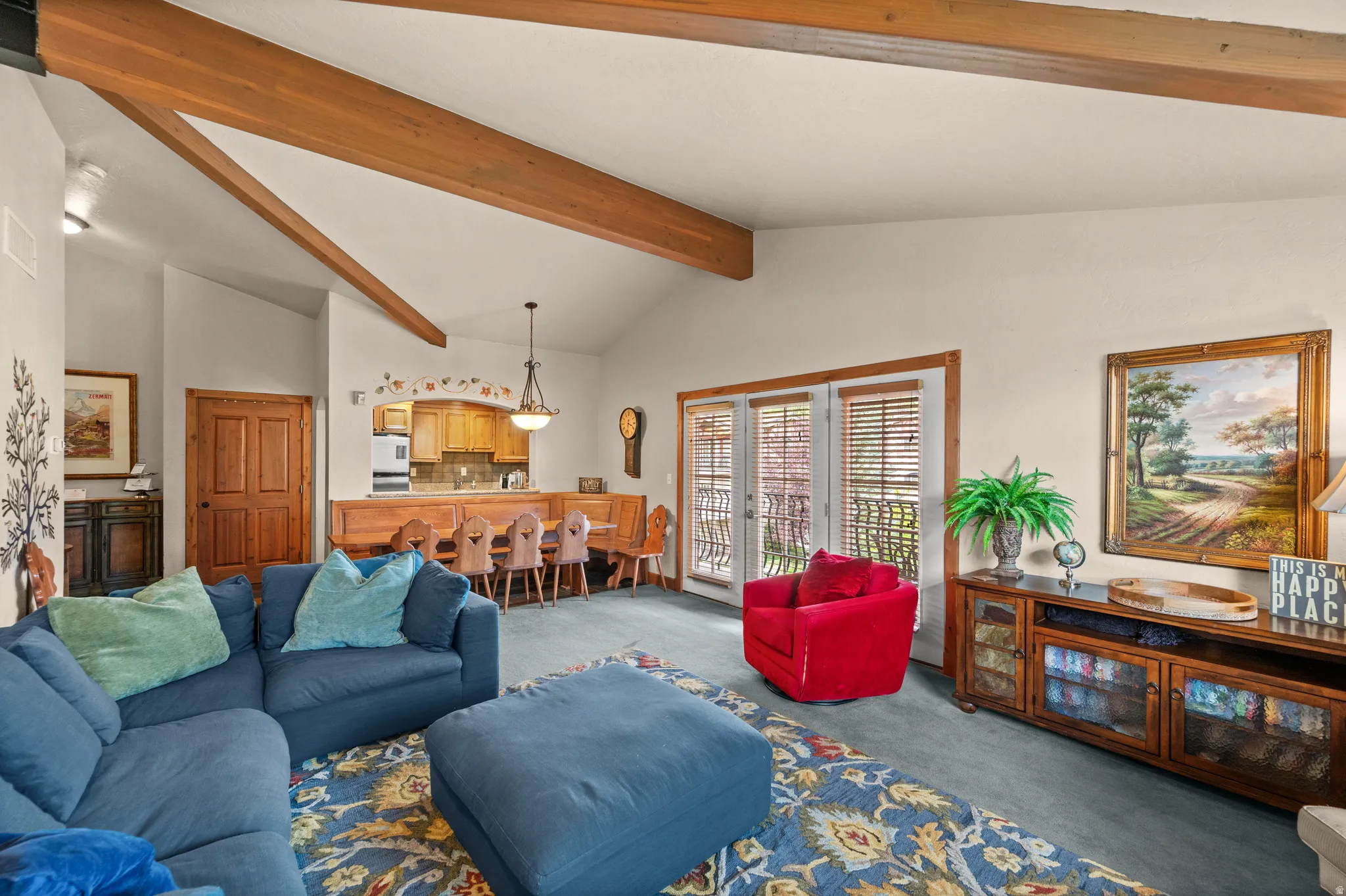 Vaulted ceilings with exposed wood beams, French doors with integrated blinds, and a built-in kitchen pass-through with cabinetry