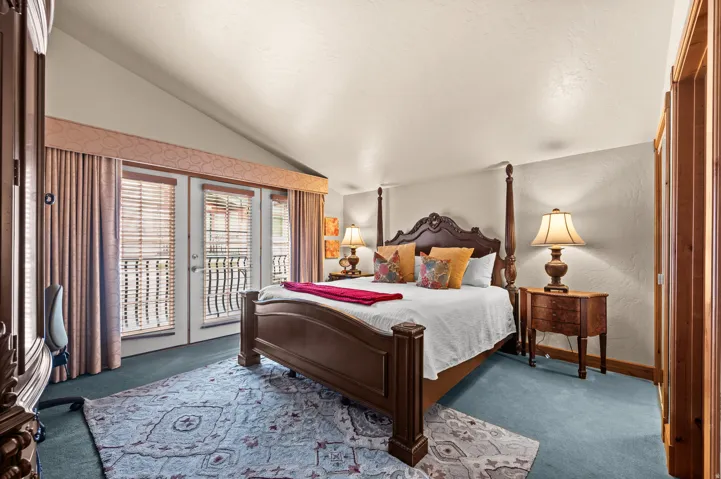 Vaulted ceiling, direct balcony access, wood-finish doors, wood-finish trim, and carpet flooring