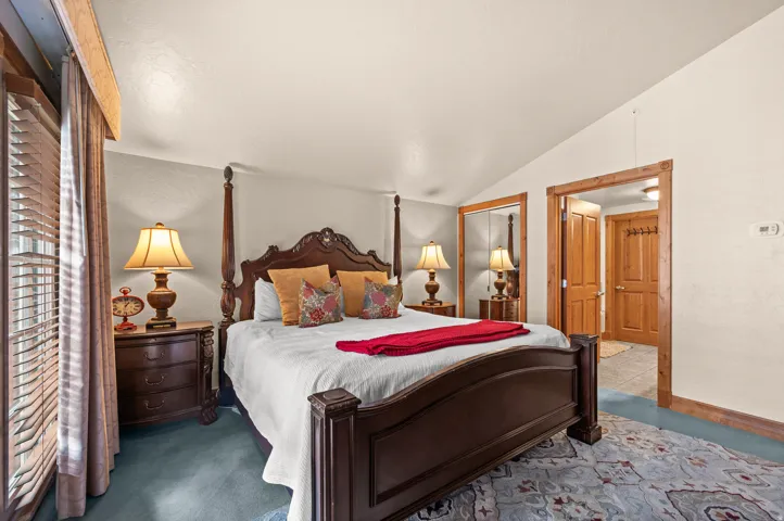 Vaulted ceiling with an exposed wood beam, wood-trimmed doorway, and a mirrored closet