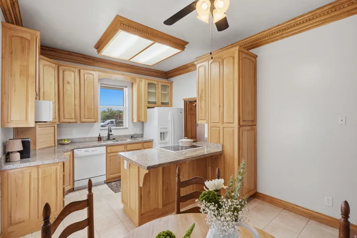 Kitchen featuring extensive wood cabinetry, granite countertops, tile flooring, and a recessed ceiling light fixture