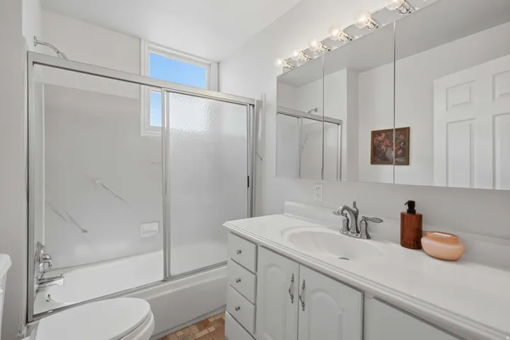 Bathroom featuring a white vanity with integrated sink, chrome-finish faucet, and a large mirrored medicine cabinet with strip lighting