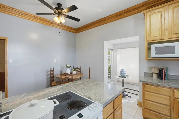 Kitchen featuring light-tone wood cabinetry, granite-finish countertops, and a built-in microwave