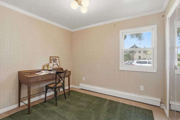 Wallpapered walls with crown molding, a single hung window, and a wall-mounted light fixture