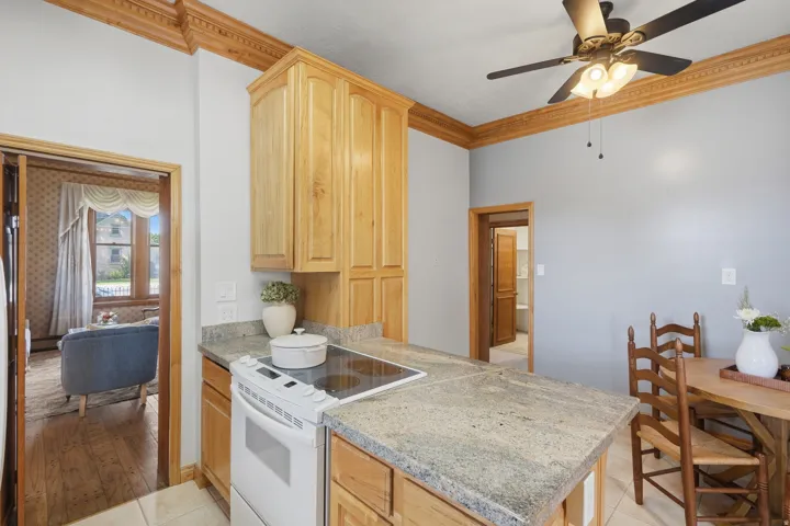 Light wood cabinetry with integrated oven, granite-finish countertops, and decorative crown molding