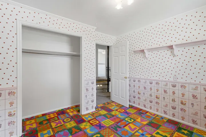Room featuring patterned carpeting, built-in shelving, an interior door, and a closet with a built-in rod