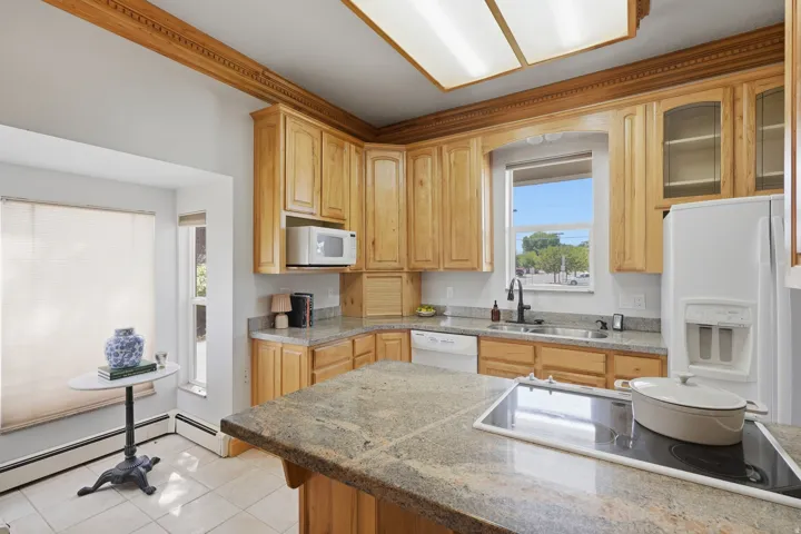Kitchen featuring wood-finish cabinetry, built-in microwave, integrated dishwasher, and a refrigerator