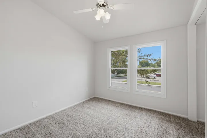 Recessed ceiling fan with light fixture, dual pane windows, and neutral carpeting